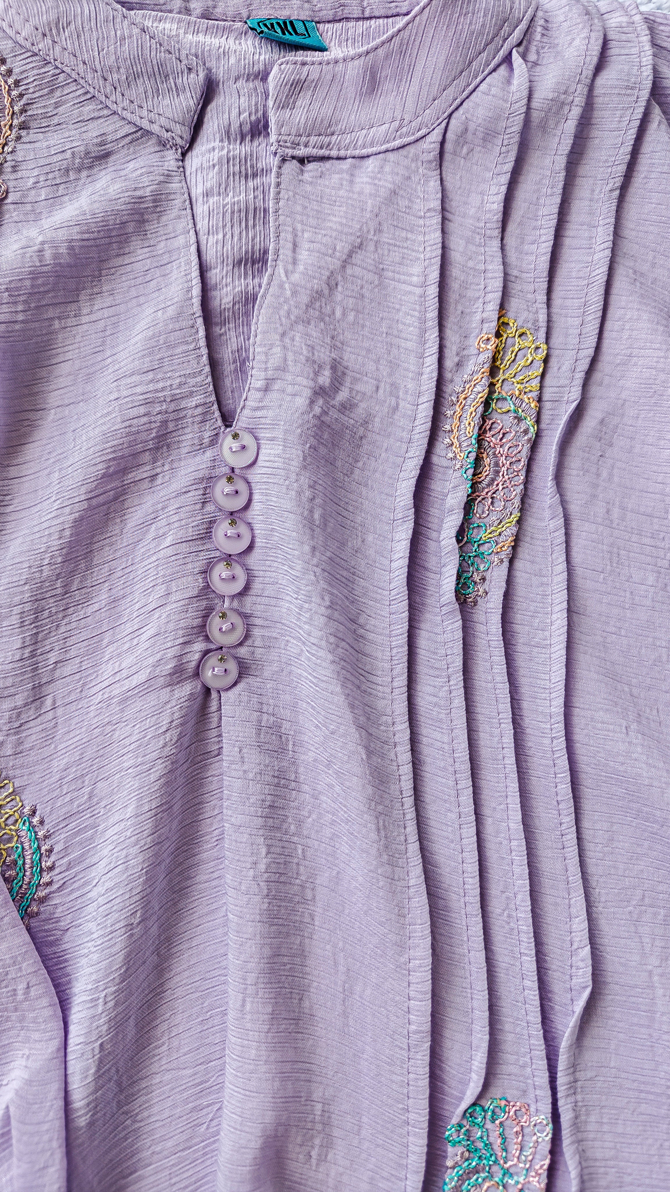 close up of purple long-sleeve women's blouse with colorful embroidered designs 