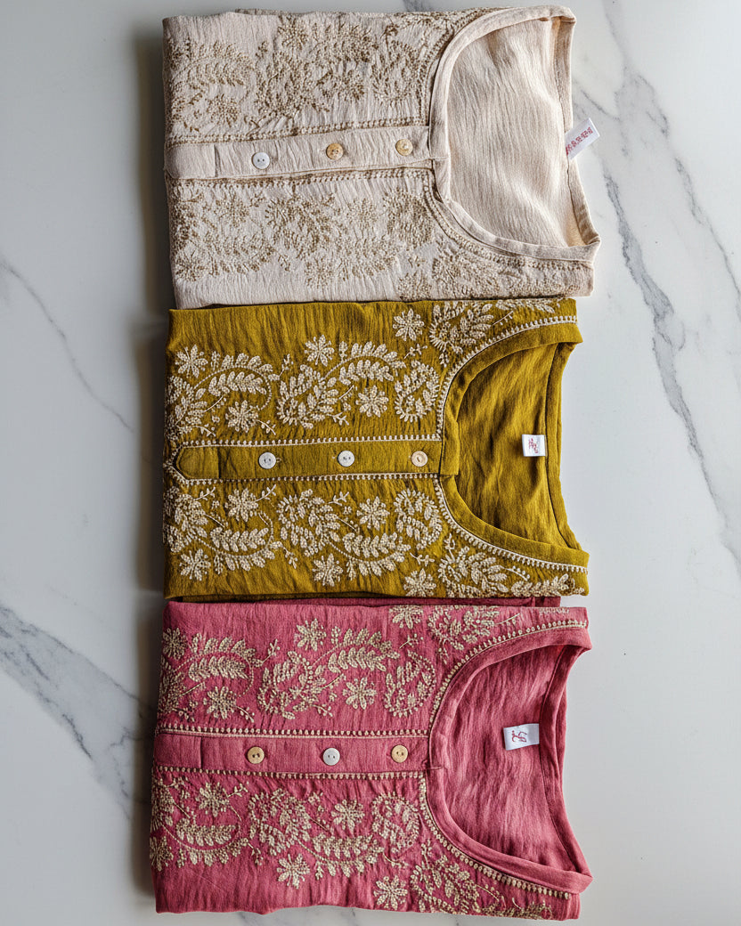 Georgette embroidered tops in beige, green, and pink on a marble surface.