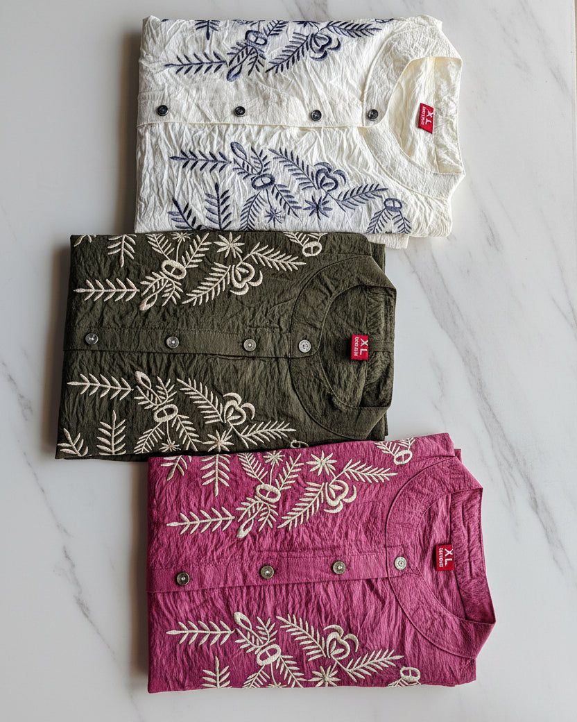 Three embroidered women's shirts in white, green, and pink
