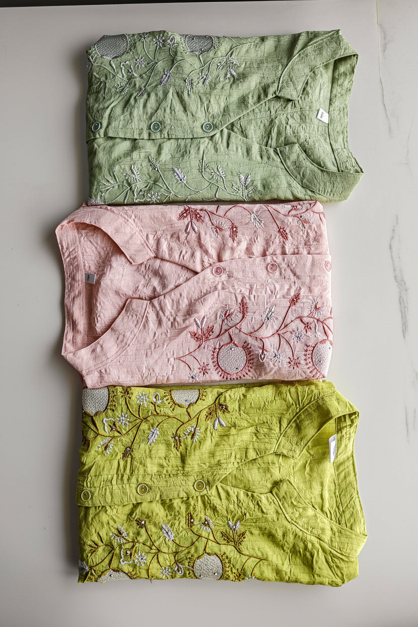 Three folded women's shirts in green, pink, and yellow with floral patterns